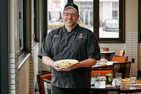 The HC Tavern + Kitchen Executive Chef Holding a Plate of Pasta